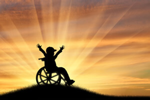 Child in wheelchair with arms raised for happiness